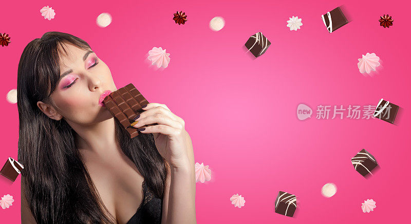 女人和巧克力。美丽的年轻女子正在吃粉红色背景上的巧克力。