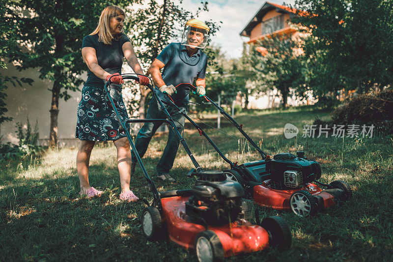 一对成熟的夫妇在后院修剪草坪