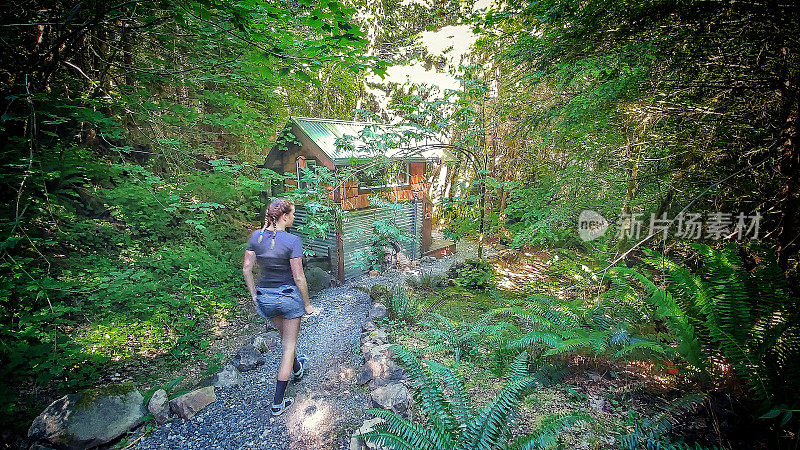 度假露营者沿着小路走到树林里的小屋