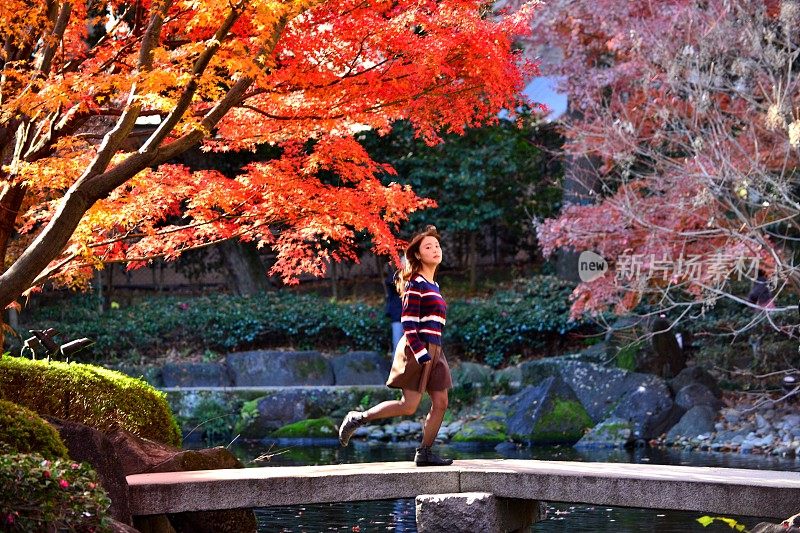 在东京日本花园的石桥上奔跑的年轻日本女人