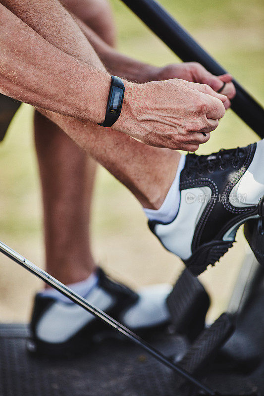 男性高尔夫球手佩戴健身追踪器系高尔夫球鞋鞋带