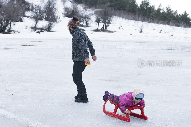 父亲带着孩子们玩雪橇