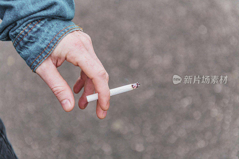 手里拿着一支点燃的香烟。