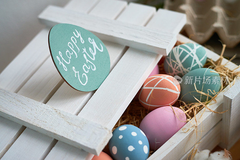 特写的彩色复活节彩蛋在木箱与贺卡封面上，油漆鸡蛋在干草