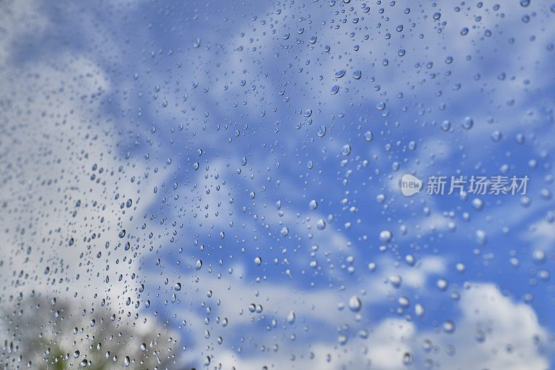 暴风雨过后，透过窗户可以看到蓝天和白云的雨滴。