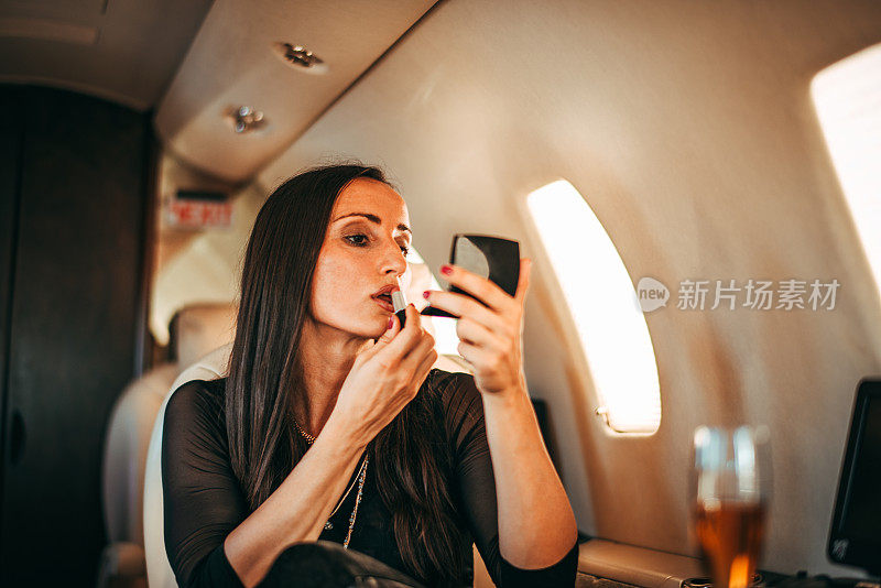 成功女性在私人飞机上用小镜子补妆