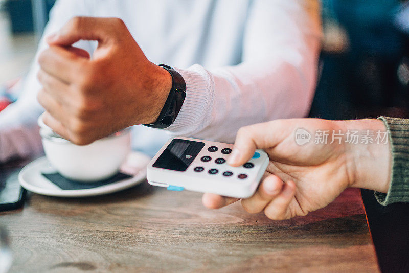 一名男子在咖啡馆用智能手表支付非接触式支付