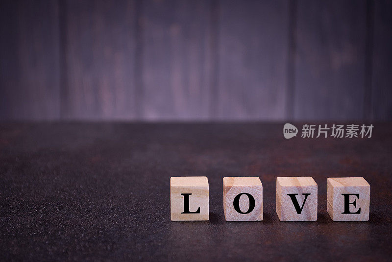 “爱”字在木方上，在深色的背景上，木方上有浅色的符号、符号