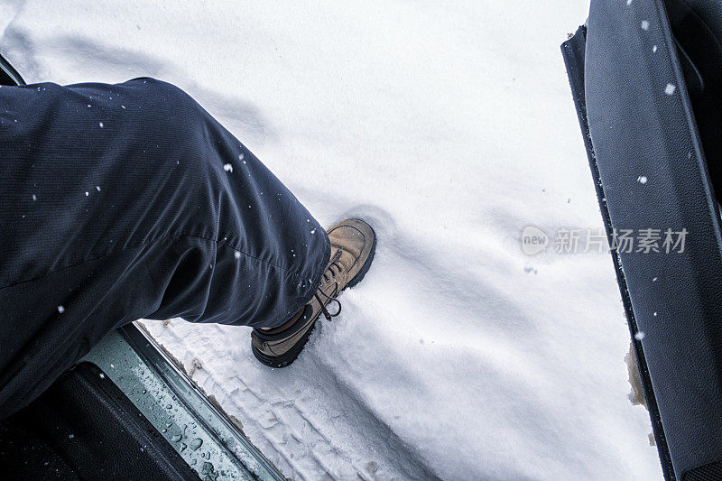 男人的腿和鞋退出汽车进入冬天的雪