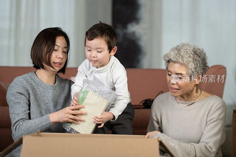 年轻的亚洲家庭和他们蹒跚学步的儿子在收拾行李