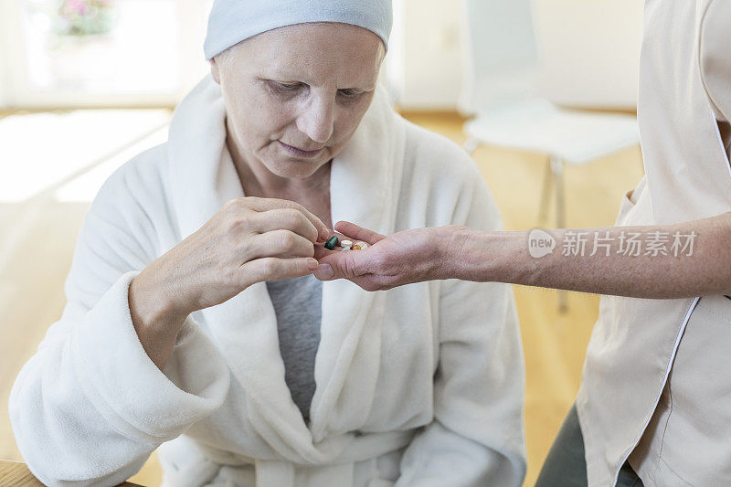 老年病人穿着浴衣和头巾在临终关怀医院从她的护士那里取药
