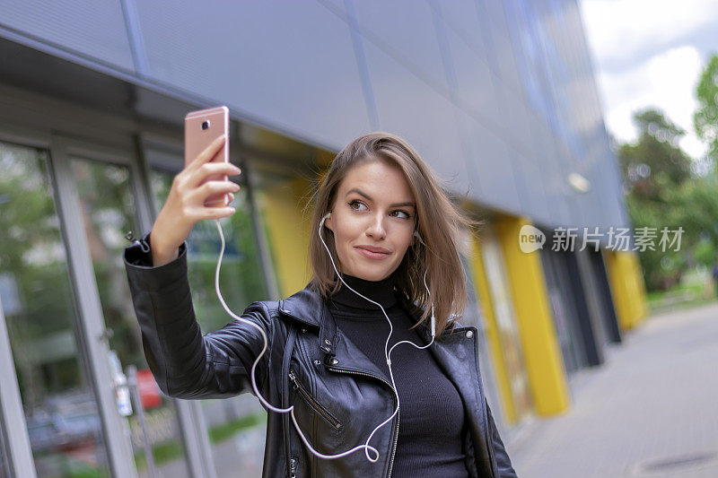 年轻迷人的女人在城市街道上自拍