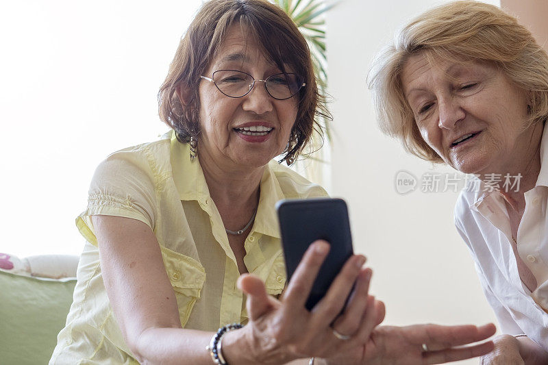 两位资深女性在家里用手机聊天
