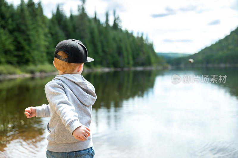 小红发男孩在夏天往湖里扔石头