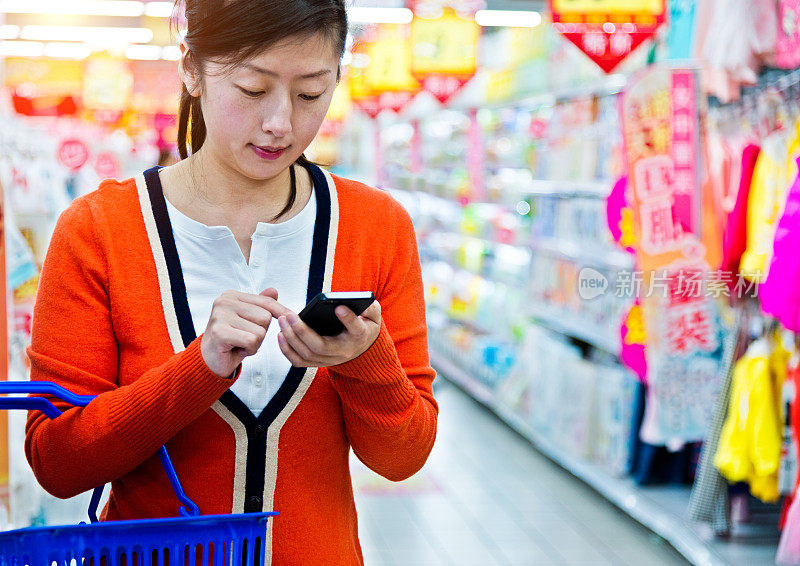 一个在超市用手机的亚洲女人