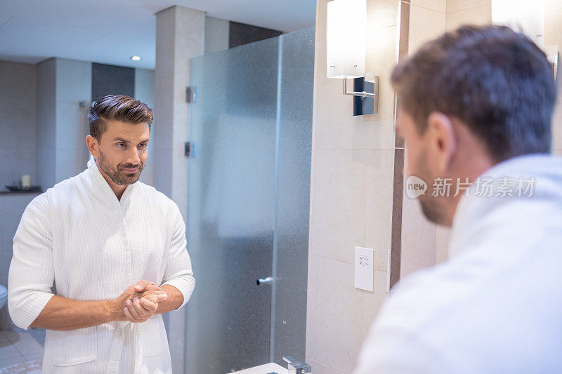 穿浴衣的男人站在浴室镜子前