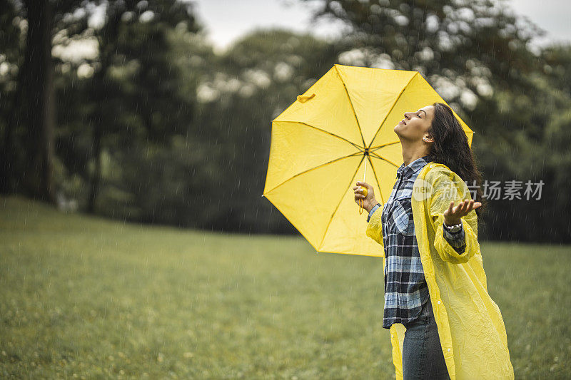 快乐的女人微笑着行走在雨天