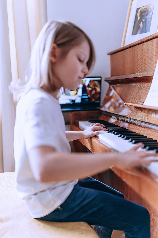 小男孩在上在线钢琴课。家庭教育。