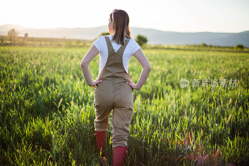 一位年轻的农妇站在麦田里