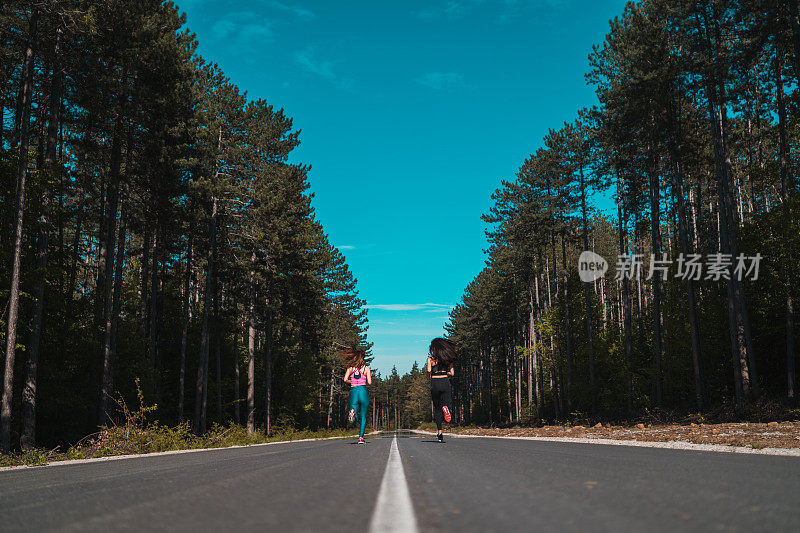 运动女孩慢跑户外柏油路松树林