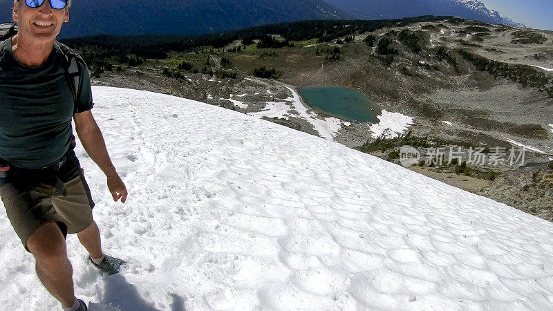 徒步旅行者沿着积雪的山坡跑下去