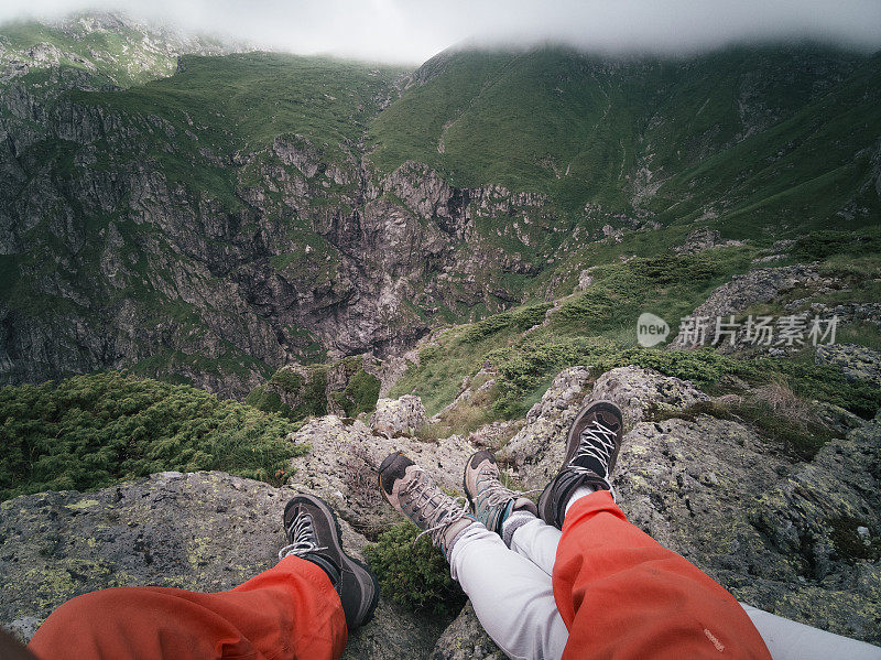 从个人角度看一对夫妇的脚在框架。回归自然。徒步旅行的游客在山上看美丽的景色。2019冠状病毒病大流行后的夏日户外享受。