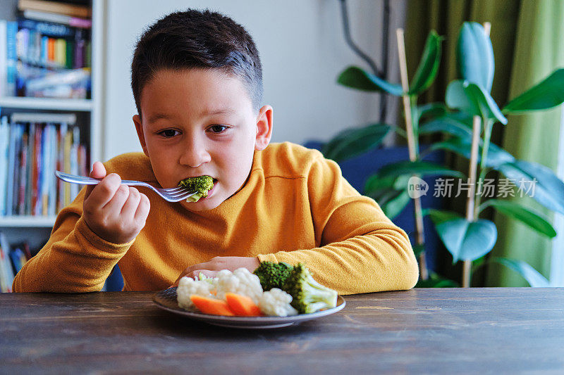 孩子对不得不吃蔬菜很不高兴。他的盘子里有许多蔬菜。他讨厌蔬菜。