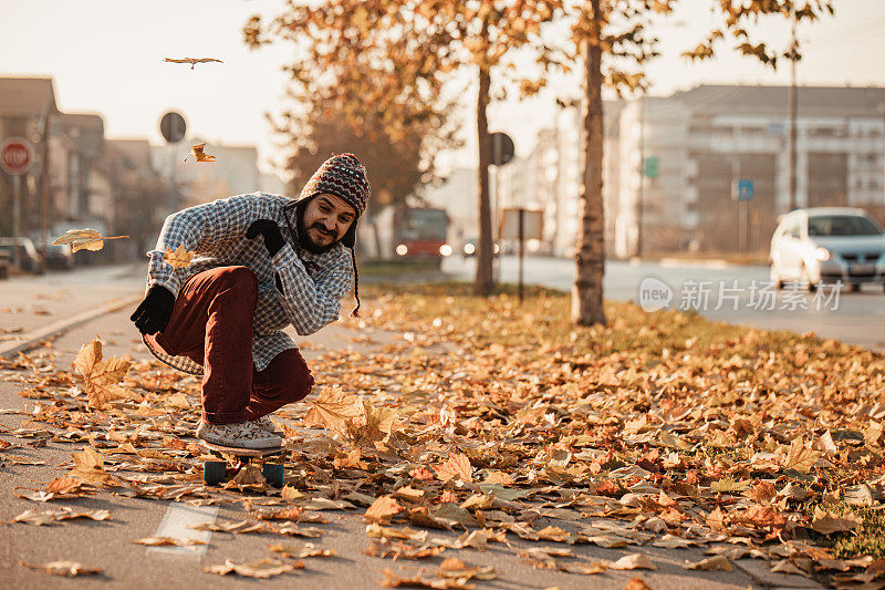 在人行道上玩滑板穿过秋叶