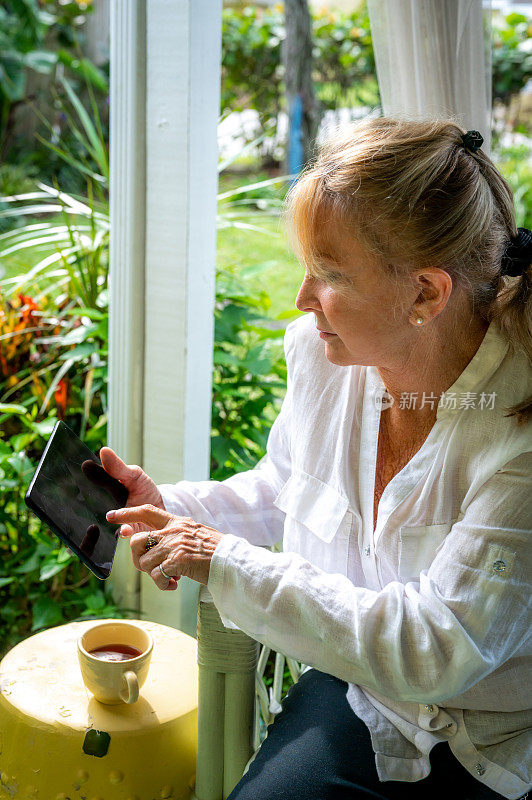 一位60多岁的妇女在户外使用平板电脑