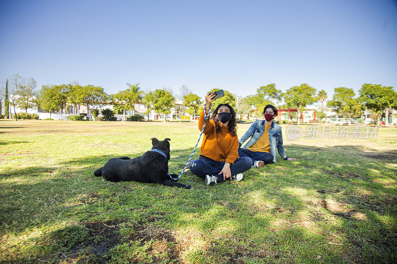 一对夫妇和一只狗坐在公园里自拍