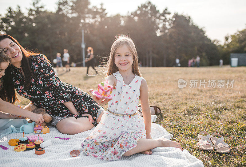 微笑的小女孩在公园野餐玩玩具