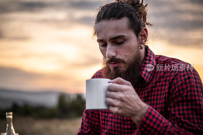 一个人在山上，一个伐木工人，一个房子给自己热茶休息辛苦的工作。