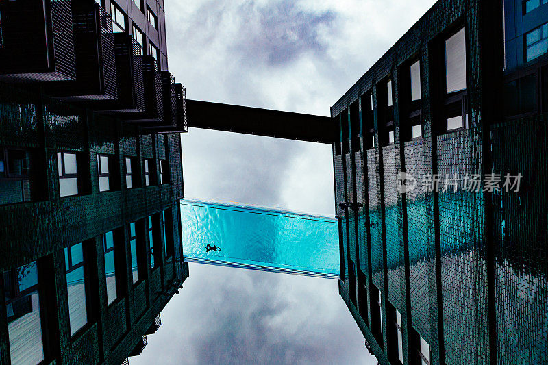 孤独的游泳者在未来的玻璃游泳池剪影