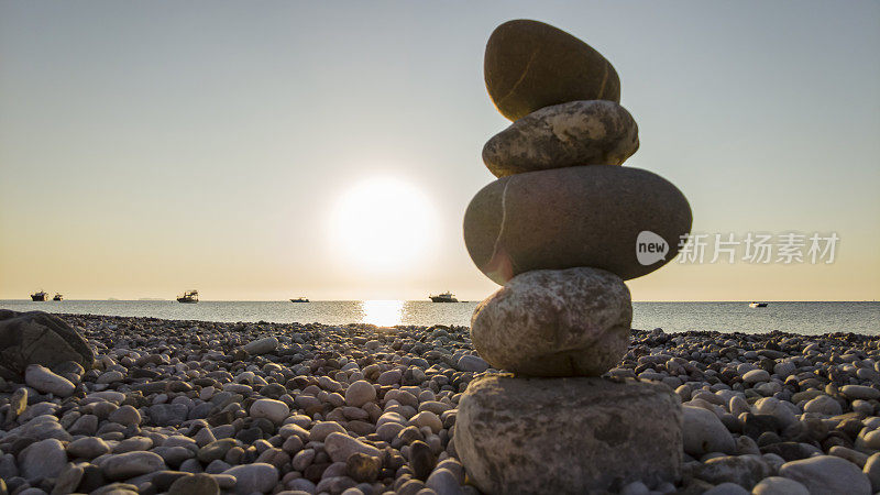 日落时在海滩上平衡石头