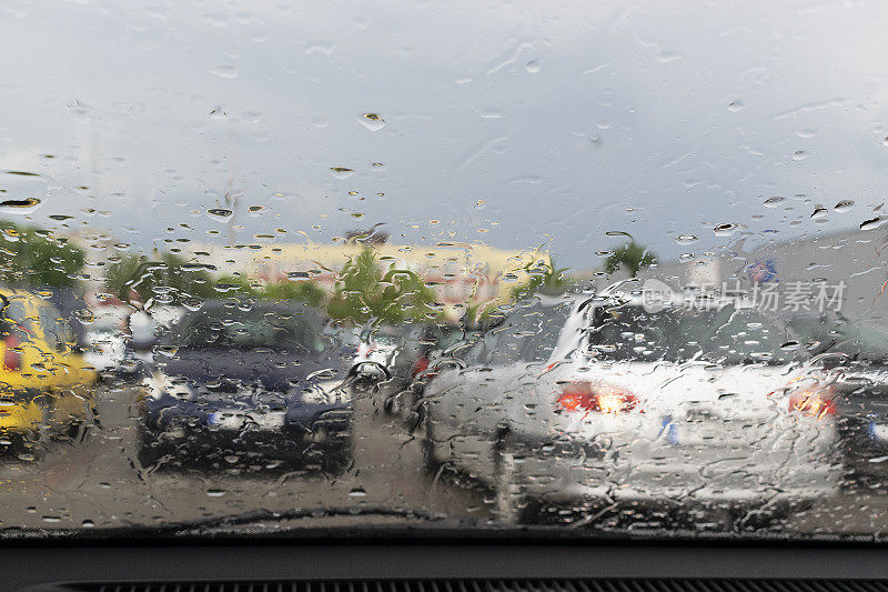 雨滴落在车窗玻璃上，勾勒出一辆车和一个人的轮廓