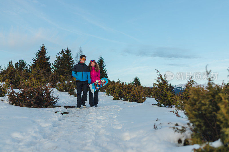 美丽的年轻异性恋夫妇在一个滑雪假期散步在自然而牵手