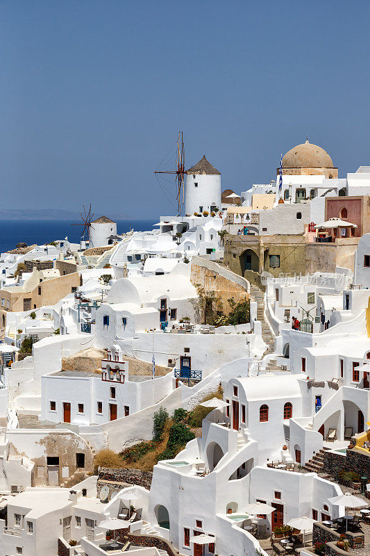 在希腊圣托里尼岛度假旅游旅游伊亚镇地中海与风车肖像格式的圣托里