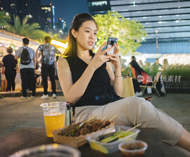 广角办公室亚洲妇女拿着电话享受放松愉快的食物和饮料街头食品当地夜市在她的办公室附近享受夜市在首都