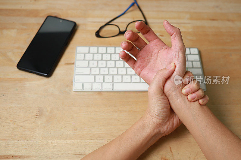 在电脑前工作时，手腕疼痛、麻木或腕管综合症的妇女用手握住疼痛的关节
