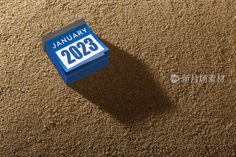 撕下的日历显示2023年新年快乐的沙子背景