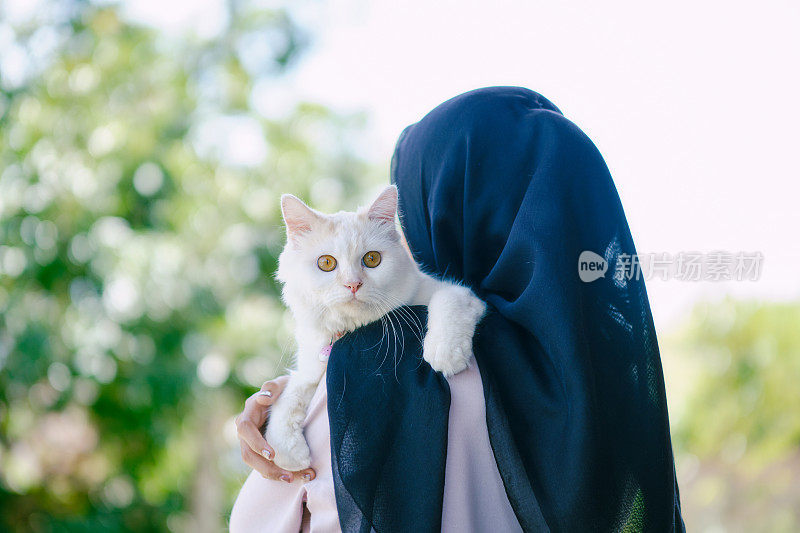 戴着头巾的女人抱着她的猫