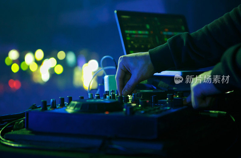 DJ在夜总会的派对上播放电子音乐。近距离照片的唱片骑师混合音乐轨道与midi控制器设备