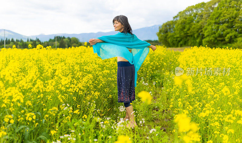 一位妇女在一片黄色的油菜花地里放松和享受户外活动