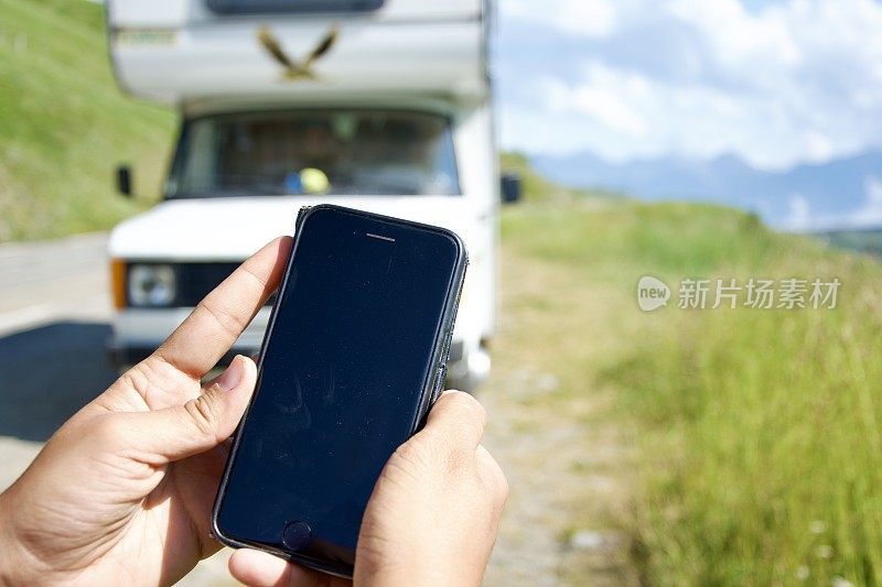 在露营车附近手持智能手机