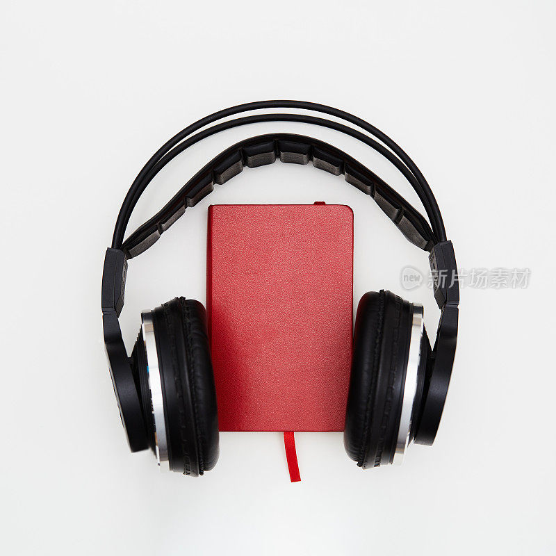 有声读物。白色背景的红皮书和无线耳机