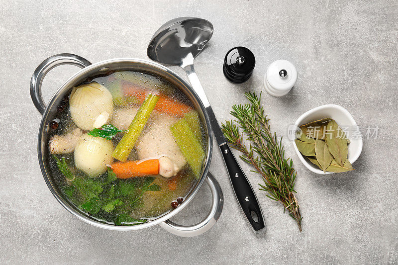 锅与美味的汤汁和不同的食材在浅灰色的桌子上，平铺