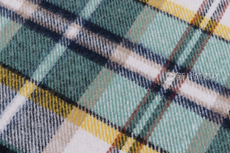 暖色格子布的特写，绿色，黄色和白色的格子布。苏格兰风格衬衫和裙子的保暖材料。设计背景