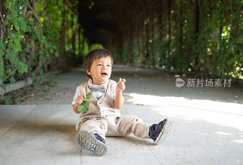 一个多种族的幼童心满意足地坐在公园的小路上