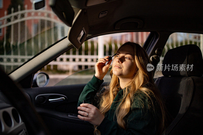年轻女子坐在车里涂睫毛膏