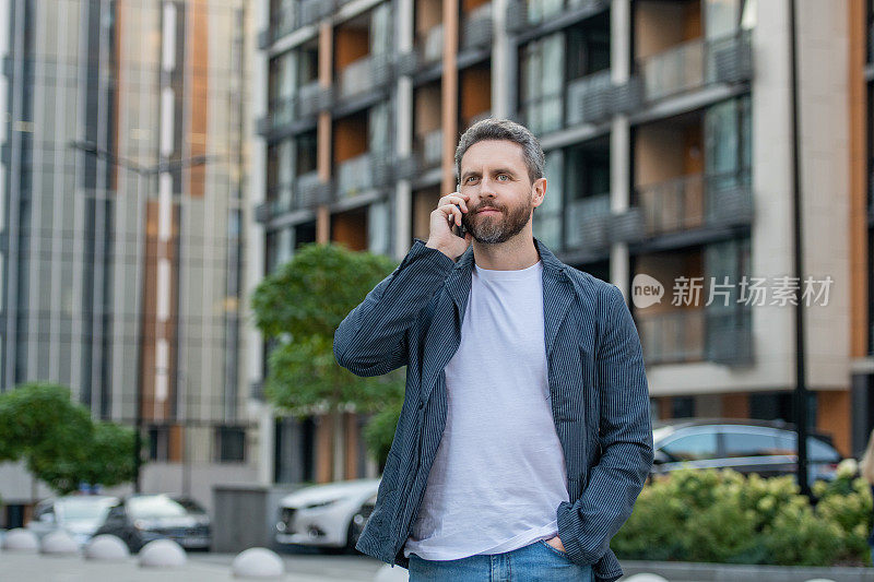 成年男子在户外用智能手机打电话。一个人在街上用智能手机打电话。